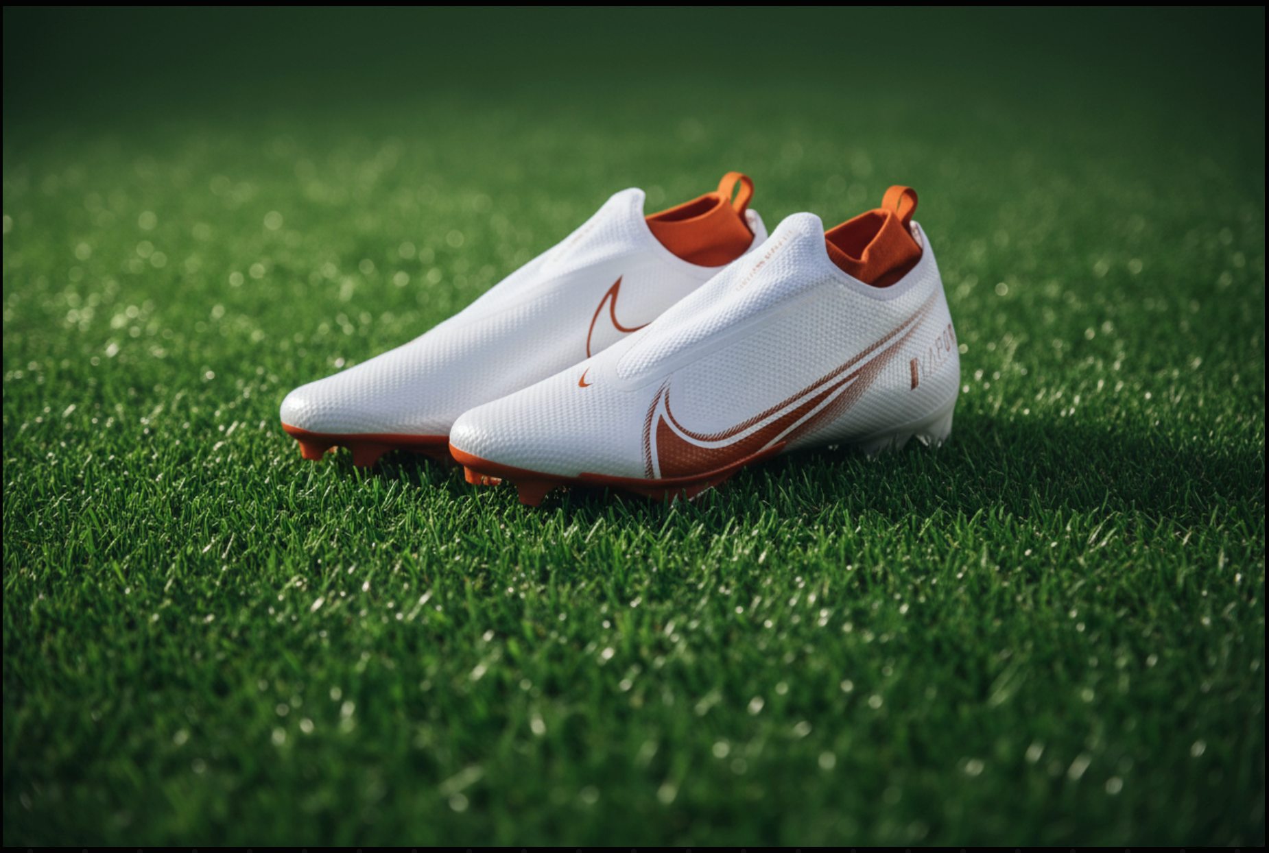 White soccer cleats with red accents on a grass field